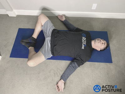 Person lying on their back with the soles of the feet together and knees open in the frog position