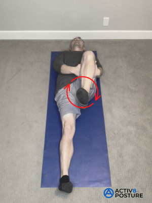 Woman lying on her back holding one knee toward her chest while circling that foot